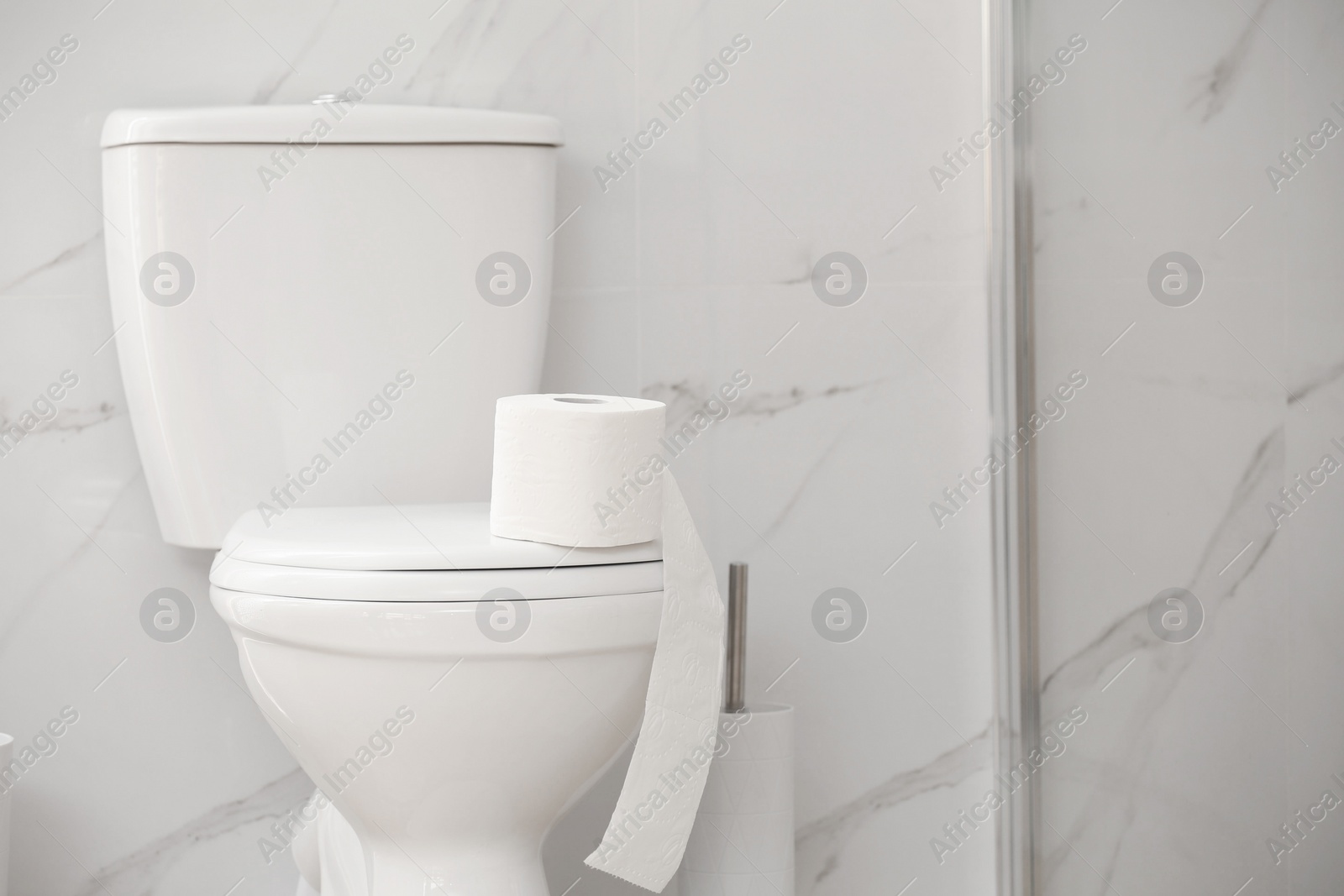 Photo of Modern toilet bowl with roll of paper in bathroom