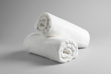 Photo of Fresh soft rolled towels on light background