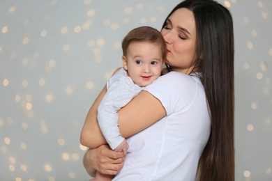 Portrait of young mother and her adorable baby against defocused lights