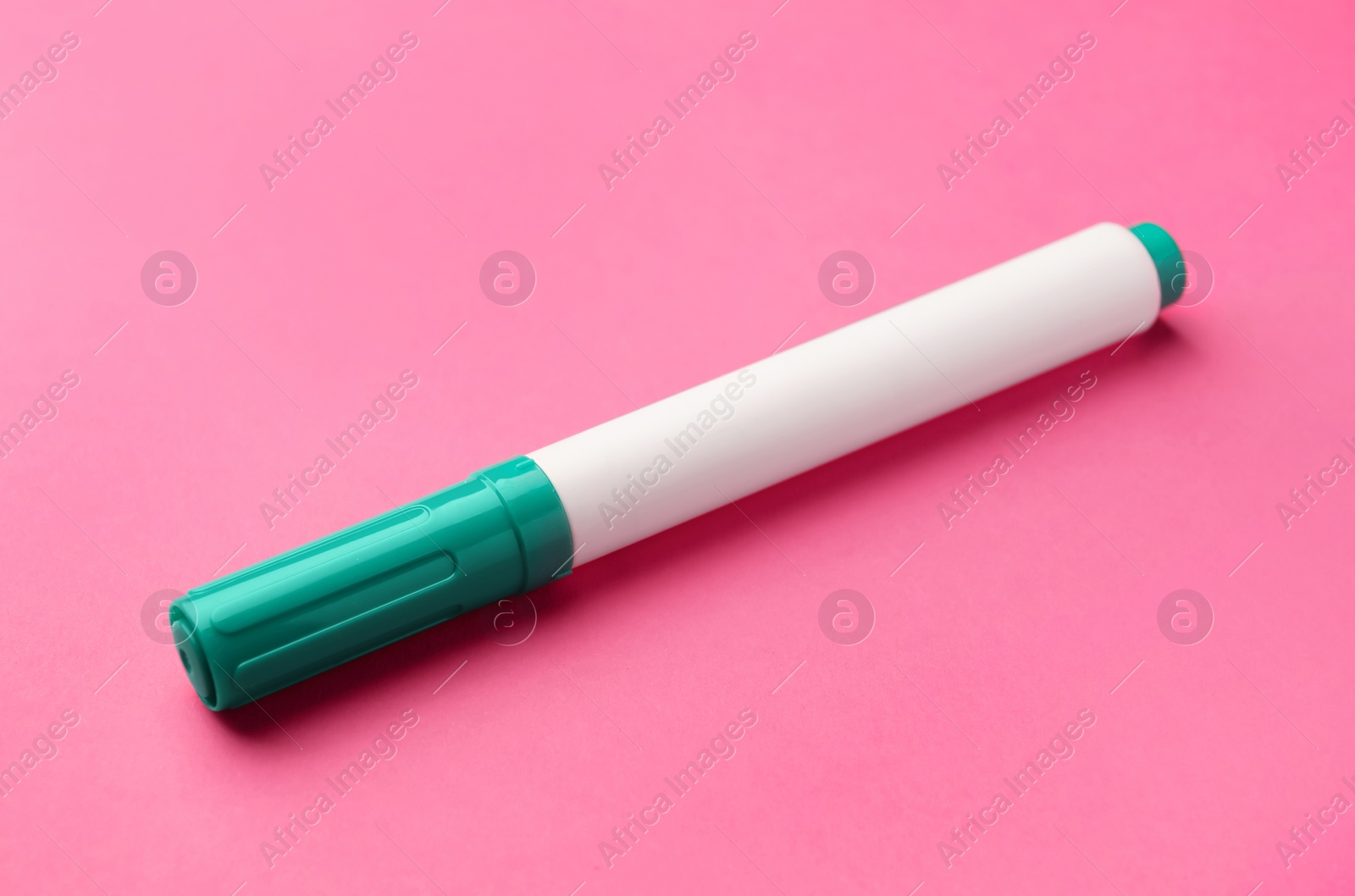 Photo of Bright green marker on pink background. School stationery