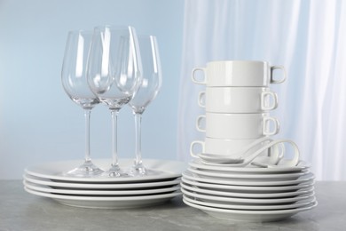 Set of clean dishware and glasses on grey marble table
