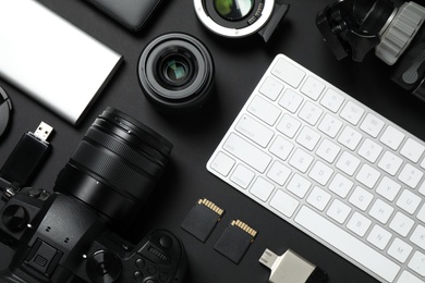 Camera, video production equipment and computer keyboard on black background, flat lay