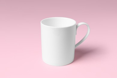 Photo of One white ceramic mug on pink background