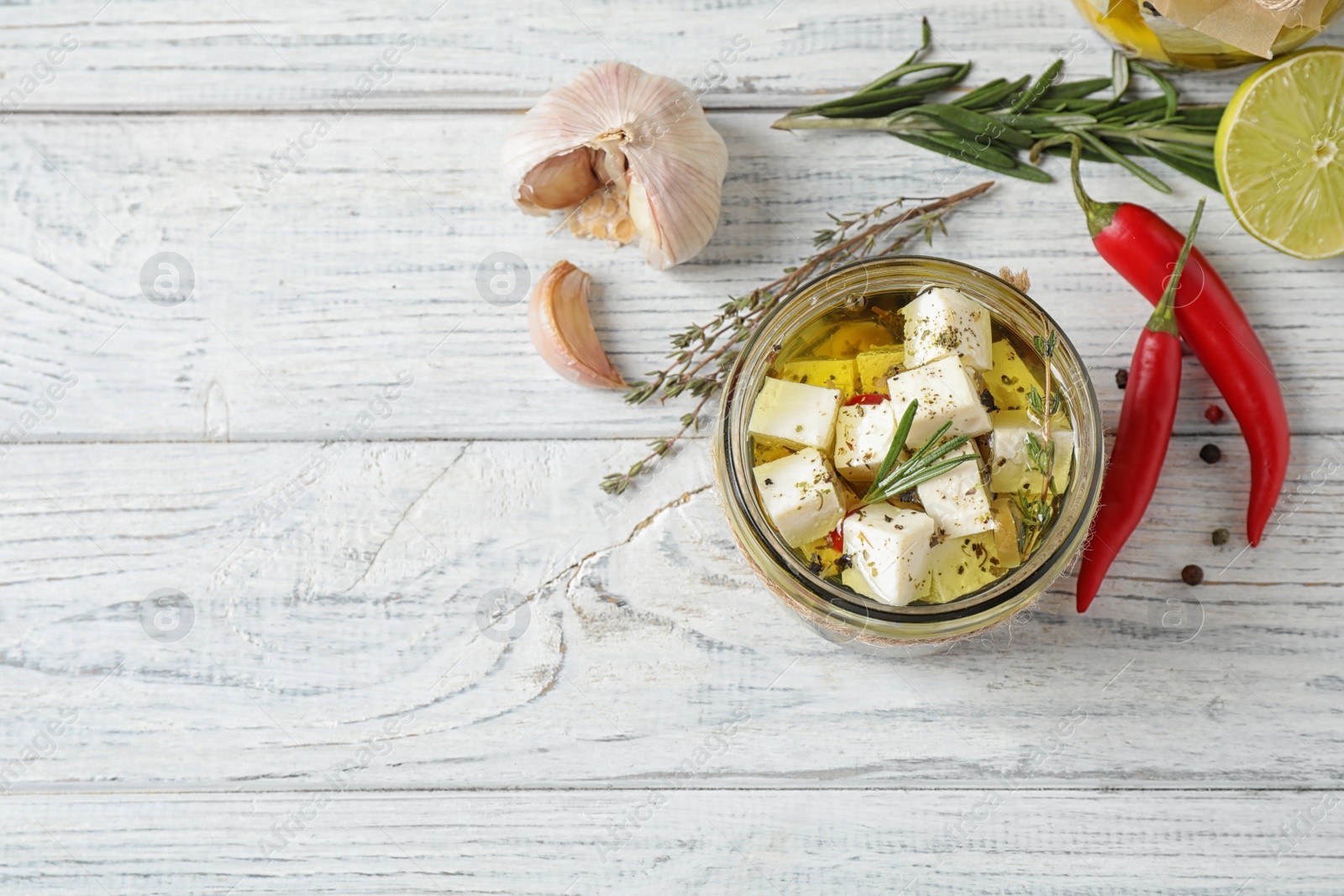 Photo of Flat lay composition with pickled feta cheese in jar on white wooden table, space for text