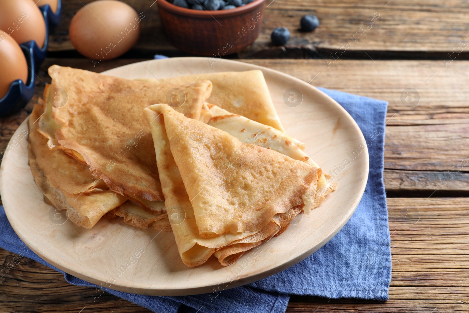 Photo of Delicious crepes served on wooden table, closeup