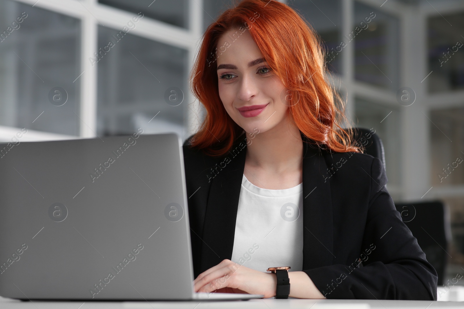 Photo of Happy woman working with laptop at white desk in office