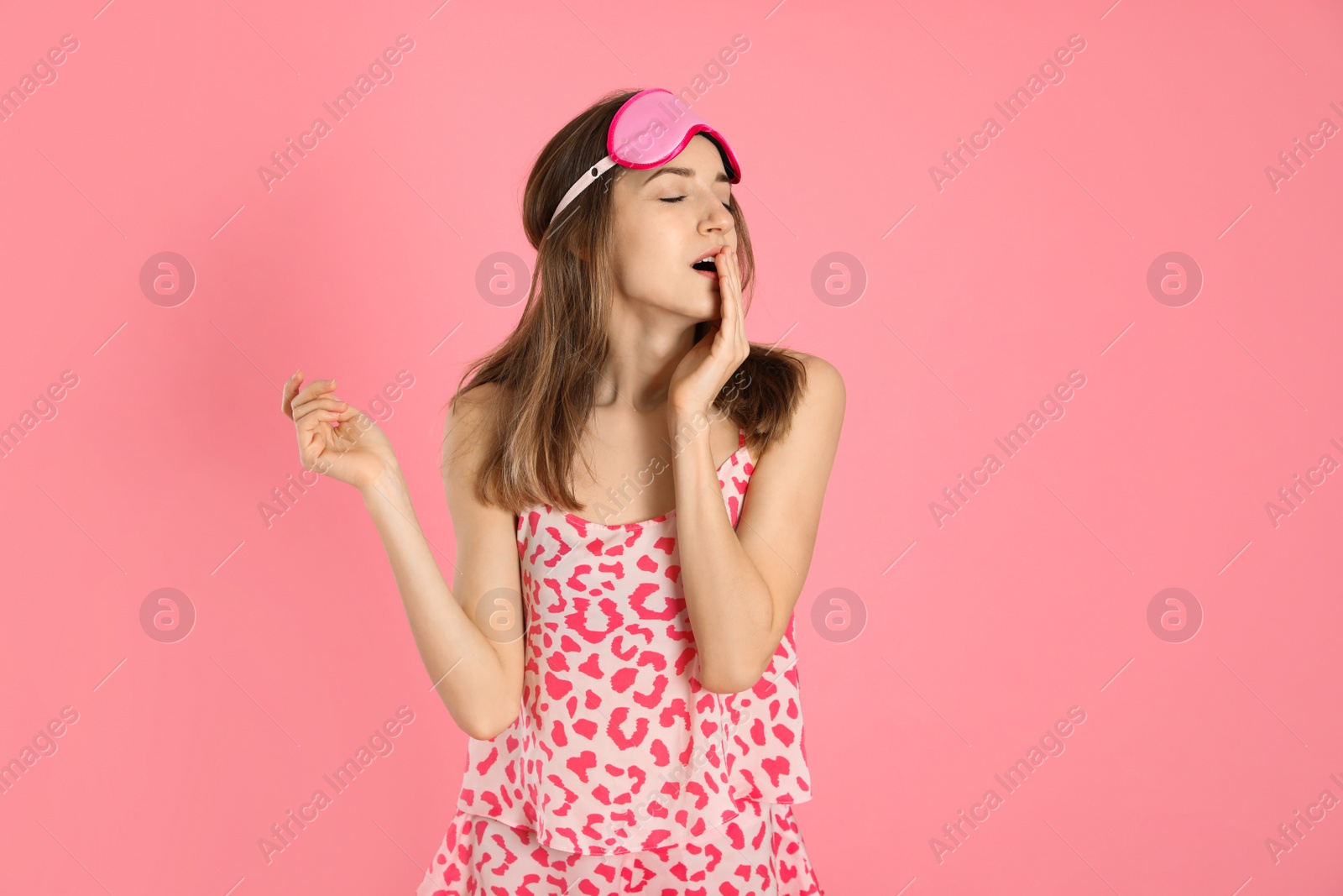 Photo of Beautiful woman wearing pajamas and sleep mask on pink background. Bedtime