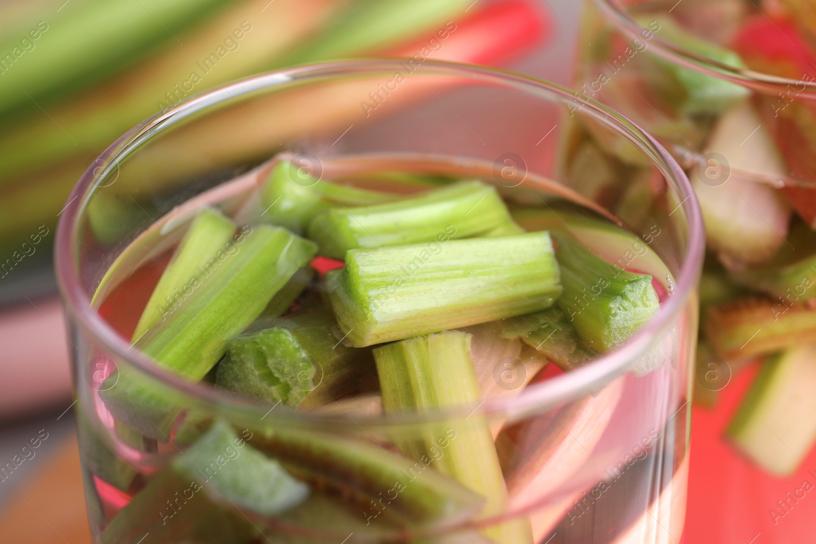 Photo of Glass of tasty rhubarb cocktail on blurred background, closeup