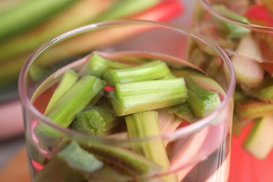 Glass of tasty rhubarb cocktail on blurred background, closeup