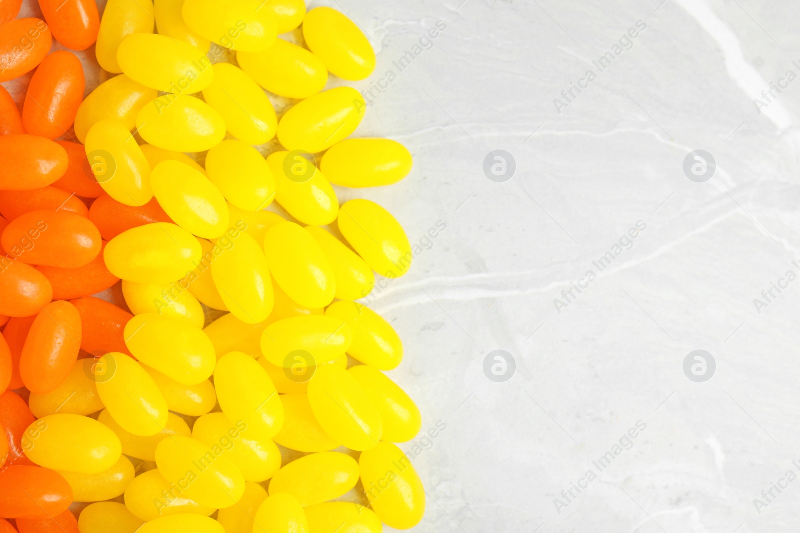 Photo of Flat lay composition with jelly beans on light background, closeup. Space for text