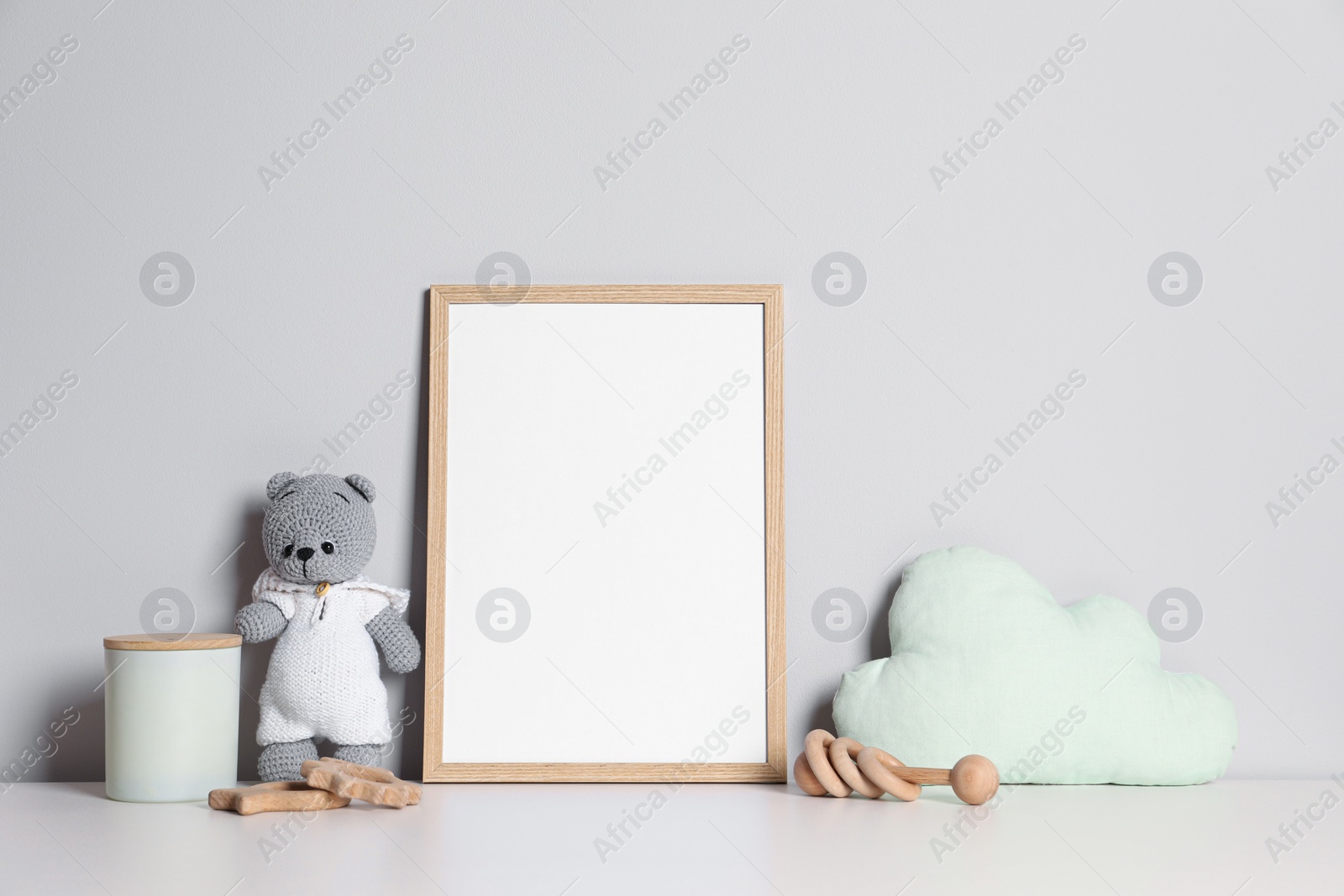 Photo of Empty square frame and different toys on white table