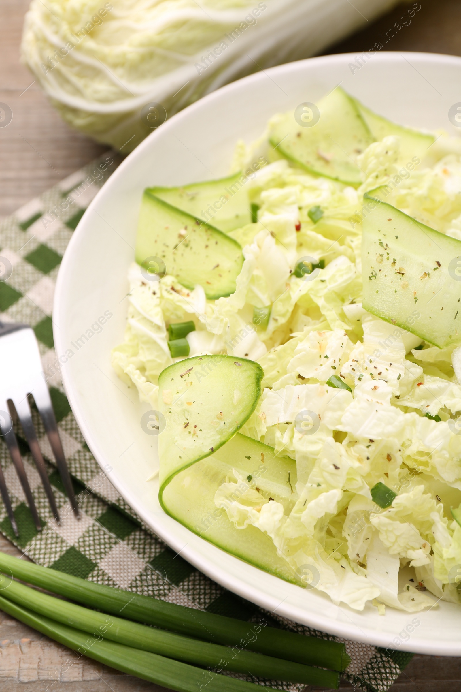 Photo of Tasty salad with Chinese cabbage, cucumber and green onion in bowl on table, closeup