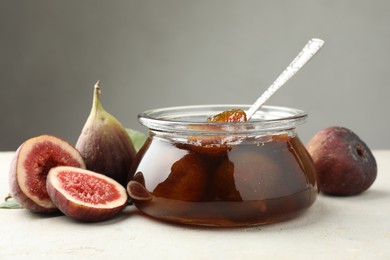 Jar of tasty sweet jam and fresh figs on white table