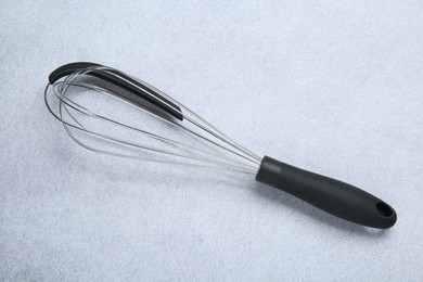 Metal whisk on gray table, top view