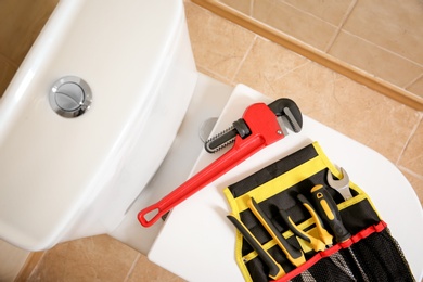 Photo of Different plumber's tools on toilet seat lid indoors