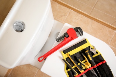 Different plumber's tools on toilet seat lid indoors