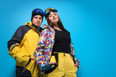 Photo of Couple wearing stylish winter sport clothes on light blue background, low angle view