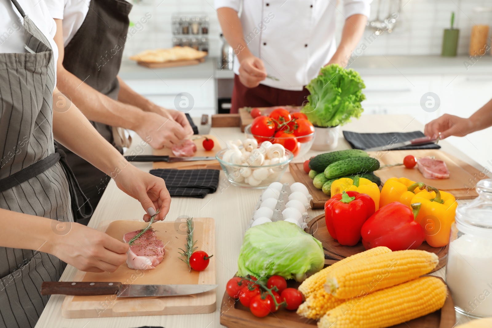 Photo of Female chef preparing meat on wooden board at table, closeup