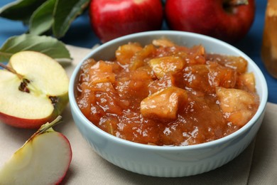 Photo of Tasty apple jam in bowl and fresh fruits on table, closeup