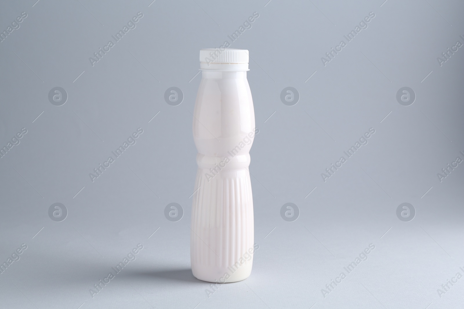 Photo of Tasty yogurt in bottle on light grey background