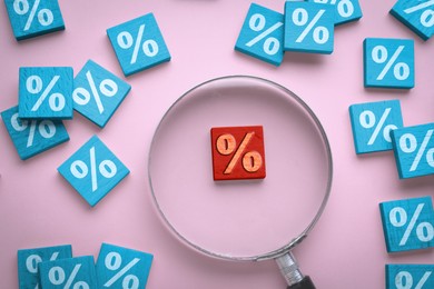 Image of Best mortgage interest rate. Red wooden square with percent sign among light blue ones on pink background, flat lay. View through magnifying glass