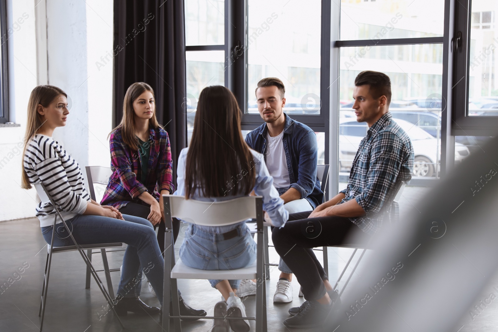 Photo of Psychotherapist working with patients in group therapy session indoors