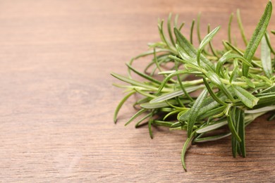 Photo of Fresh green rosemary on wooden table, closeup. Space for text