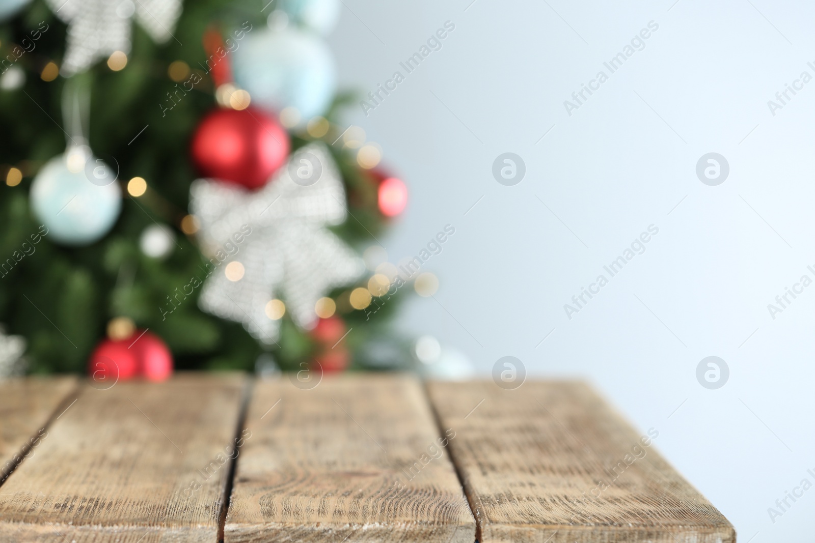 Photo of Empty wooden table and blurred fir tree with Christmas lights on background, bokeh effect. Space for design