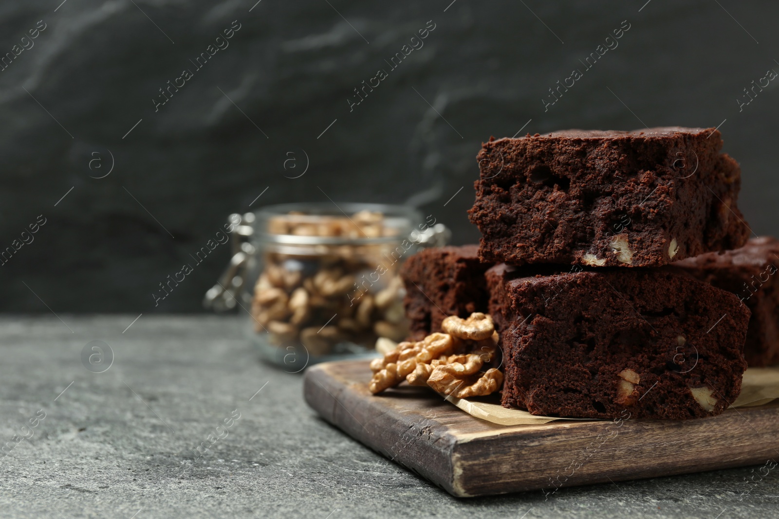 Photo of Delicious chocolate brownies with nuts on grey table, space for text