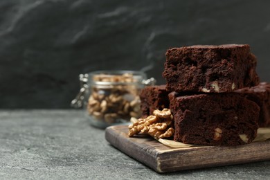 Delicious chocolate brownies with nuts on grey table, space for text