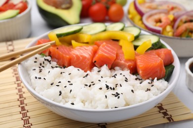 Delicious poke bowl with salmon, rice and vegetables on table, closeup