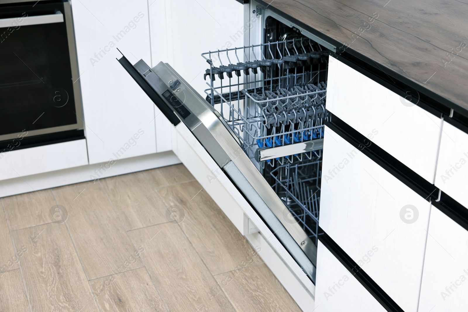 Photo of Built-in dishwasher with open door indoors. Home appliance