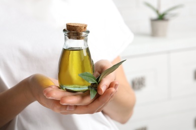 Young woman holding bottle of fresh olive oil, closeup