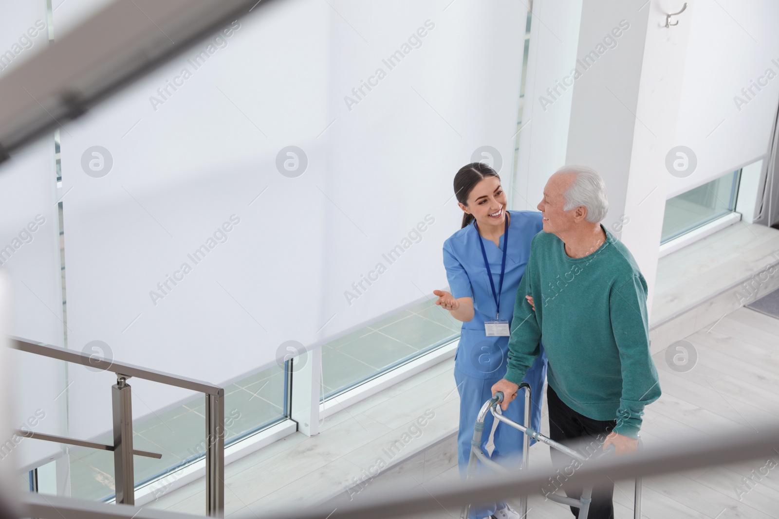 Photo of Nurse assisting senior man with walker in hospital