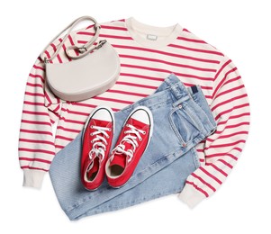 Photo of New stylish red sneakers, jeans, striped sweater and bag on white background, flat lay. Casual outfit
