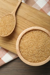 Brown sugar in bowl and spoon on table, top view