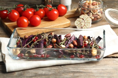 Baked black carrot with pomegranate seeds and nuts on wooden table