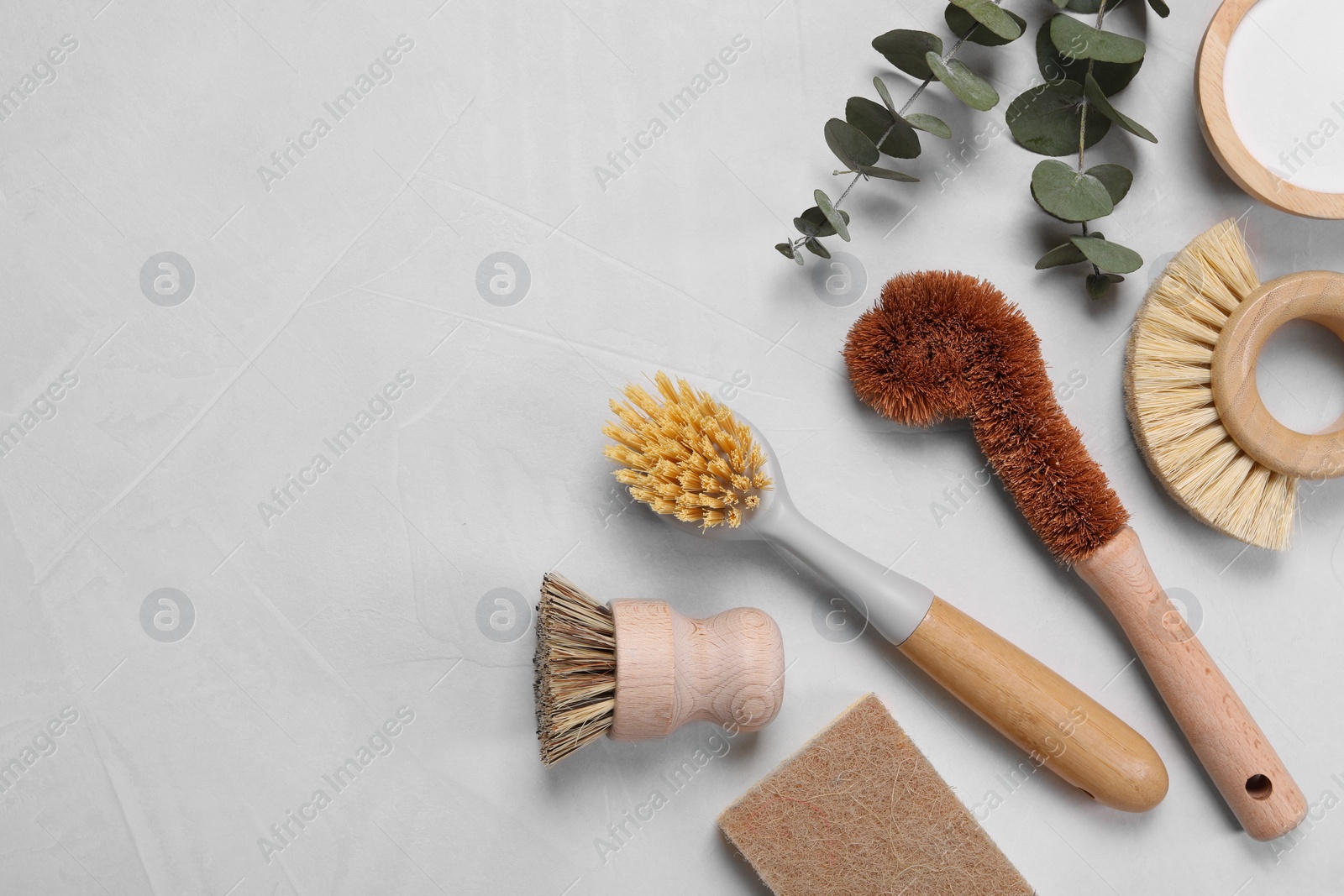 Photo of Cleaning brushes, baking soda, soap bar and eucalyptus on white table, flat lay. Space for text