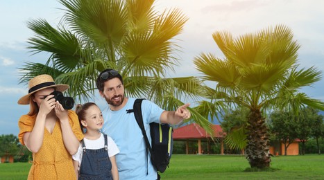 Image of Happy family with child near palm trees outdoors. Woman taking photo