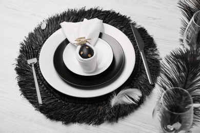 Photo of Festive table setting with bunny ears made of black egg and napkin. Easter celebration