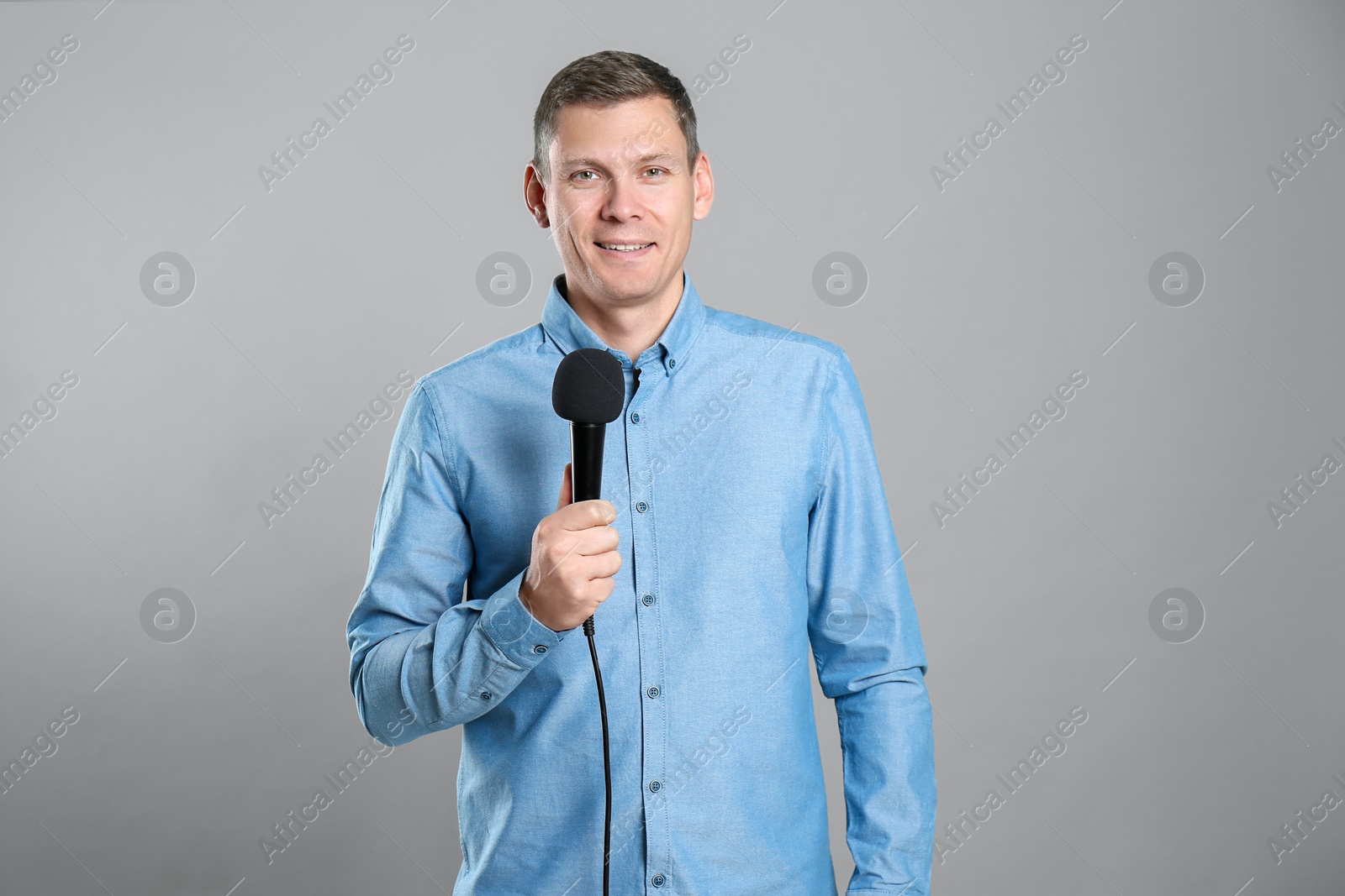 Photo of Male journalist with microphone on grey background