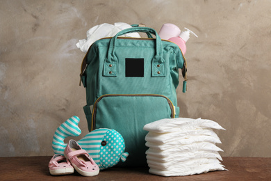 Photo of Bag with diapers and baby accessories on wooden table
