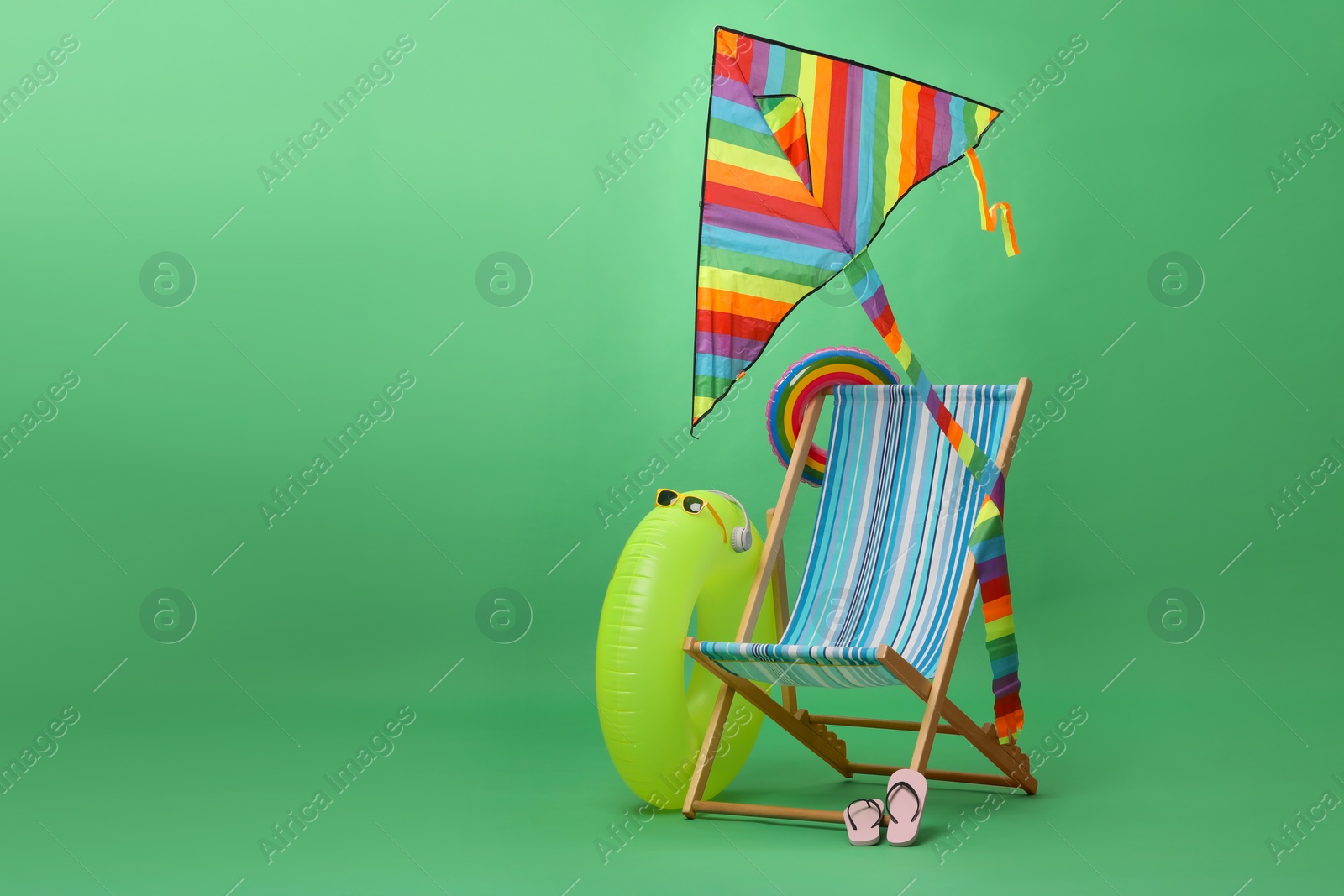 Deck chair, kite and beach accessories on green background, space for text. Summer vacation Photo of Deck chair, kite and beach accessories on green background, space for text. Summer vacation