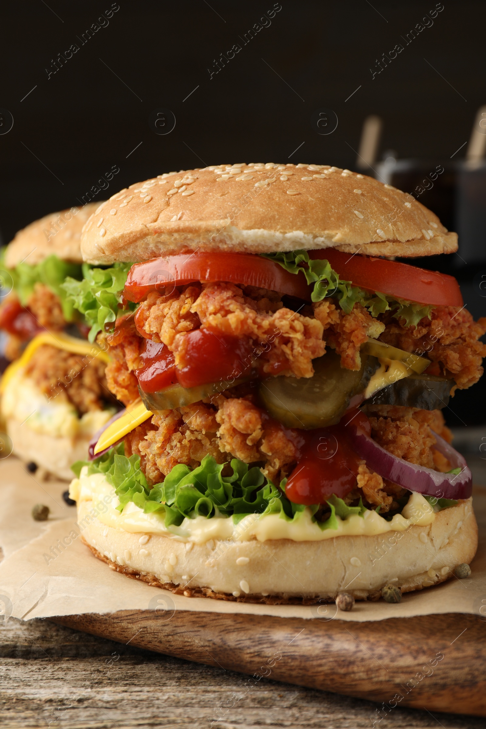 Photo of Delicious burgers with crispy chicken patty on wooden table, closeup