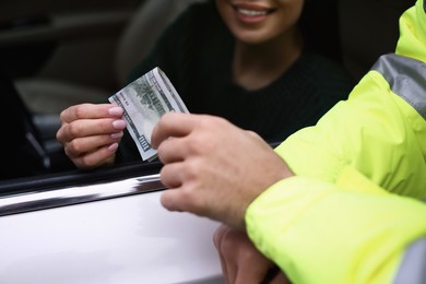 Photo of Woman giving bribe to police officer out of car window, closeup