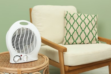 Photo of Electric fan heater on wicker table indoors. Space for text