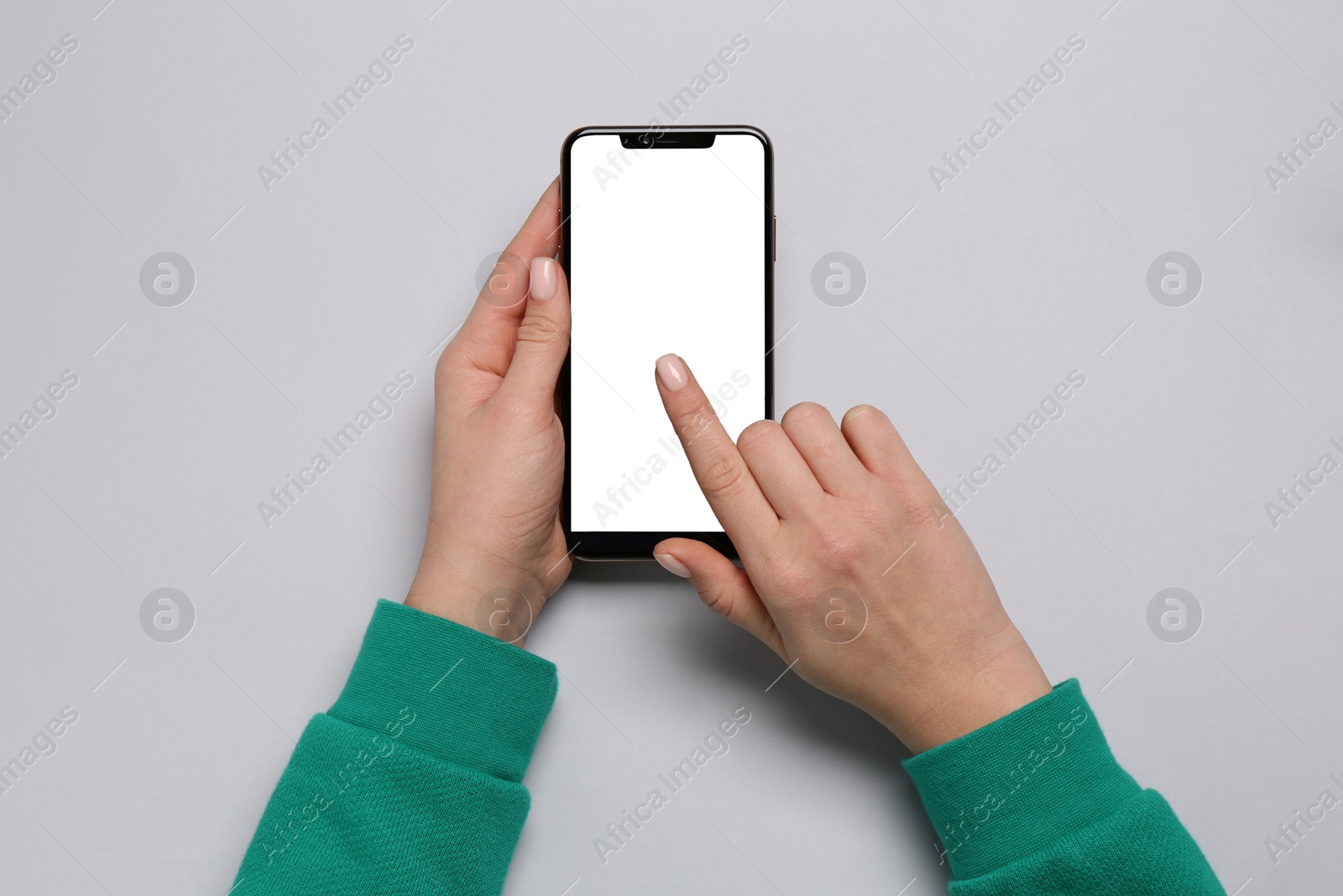 Photo of Woman using smartphone on light grey background, top view