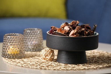 Photo of Aromatic potpourri of dried flowers and burning candles on table indoors