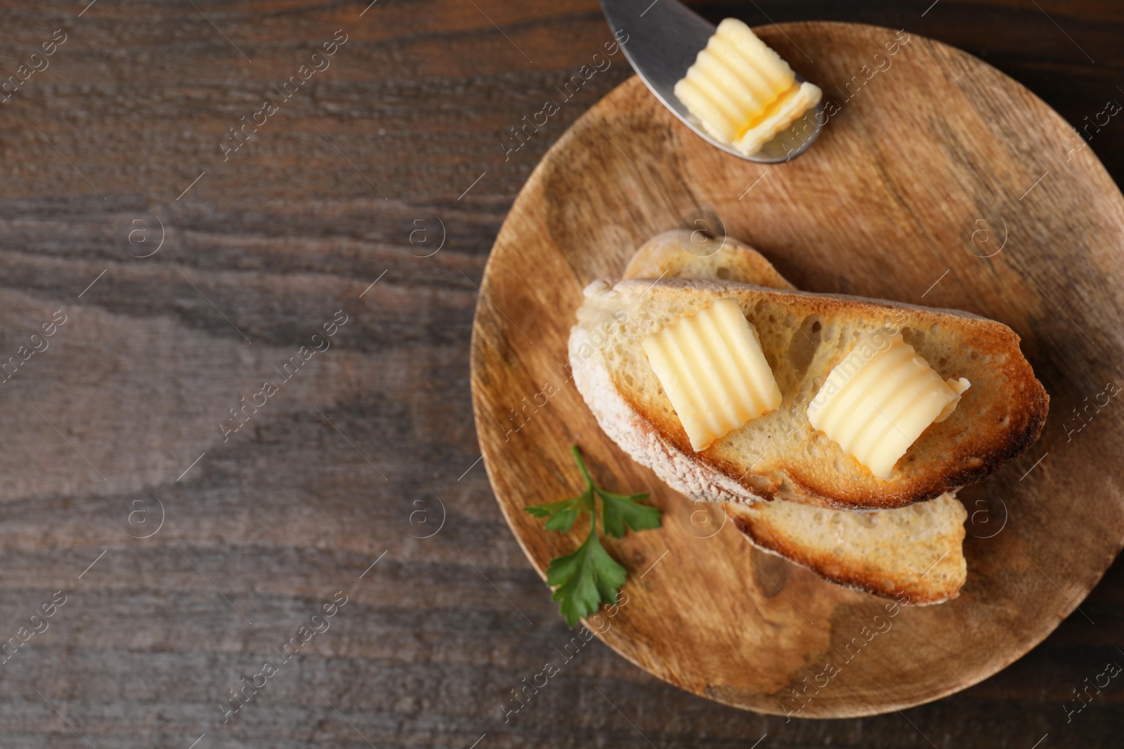 Photo of Tasty butter curls and slices of bread on wooden table, top view. Space for text