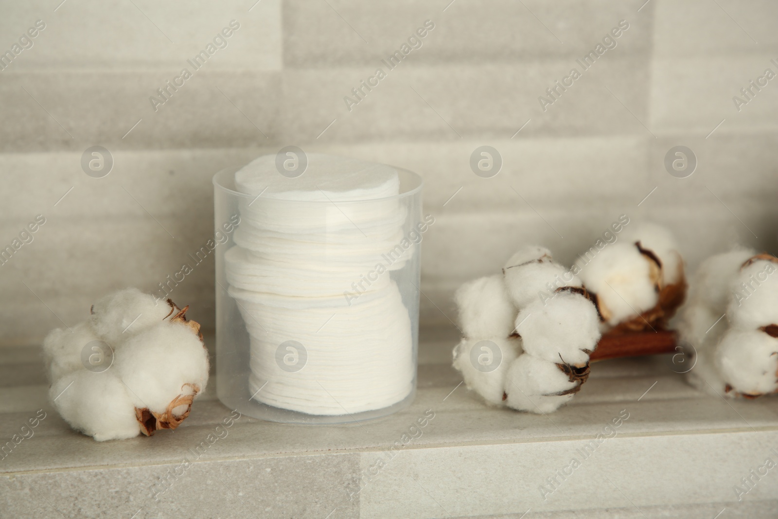 Photo of Cotton pads and flowers on tiled surface indoors